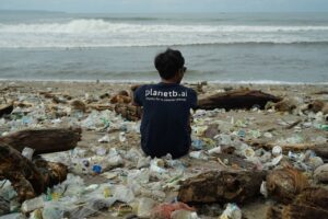 Man sitting in the sand that is full of plastic 